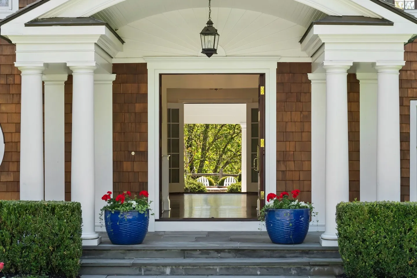 A front porch with two large blue pots on the steps.